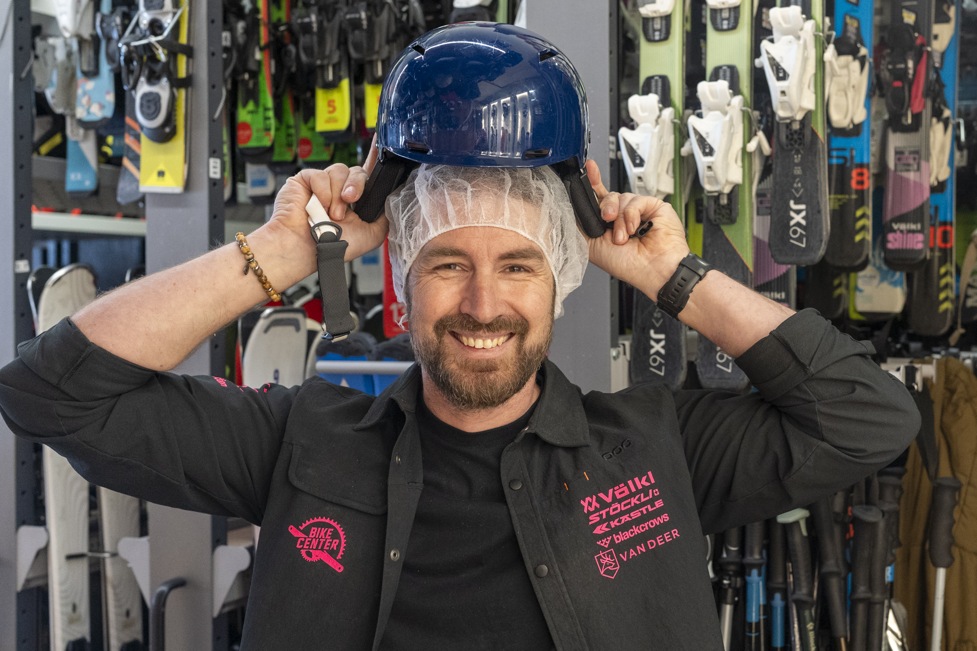 Un client souriant essaye un casque de ski propre au SKI CENTER